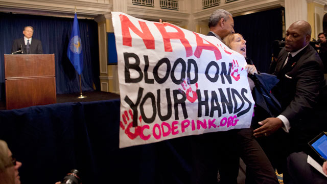 PHOTO: Activist Medea Benjamin, of Code Pink, is led away by security as she protests during a statement by National Rifle Association executive vice president Wayne LaPierre, during a news conference in response to the Connecticut school shooting, Dec. 2