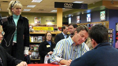 PHOTO: Rielle Hunter, left, watches John Edwards, right, as he autographs a copy of his book, "Home: The Blueprints of Our Lives" during a campaign stop in Dallas, Dec. 1, 2006.