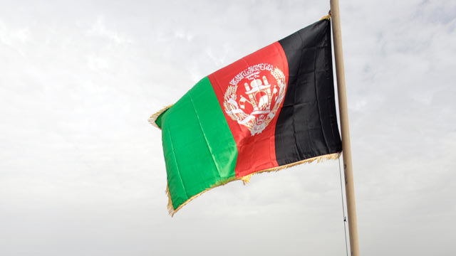 PHOTO: Afghan residents of Marjah sit at the foot of the national flag just hoisted by Helma, Feb. 25, 2010.