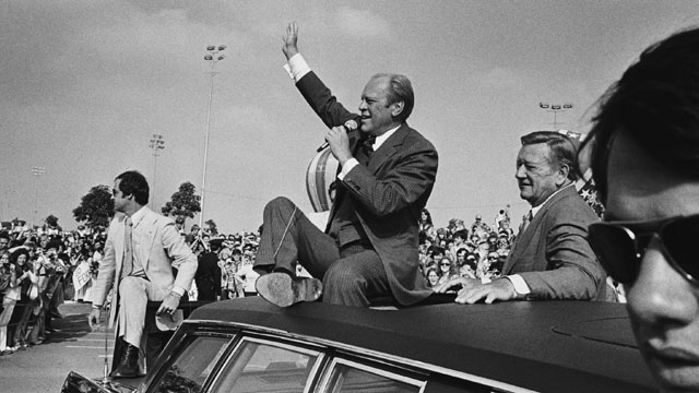 PHOTO: Accompanied by supporter John Wayne, President Ford addresses a crowd from atop his limousine in Orange County, California, during the final stretch of the campaign October 24, 1976 in Fountain Valley, Calif.