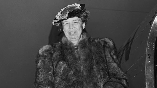PHOTO:Portrait of US First Lady Eleanor Roosevelt circa 1945, wearing a fur coat and holding a purse, smiling while standing on a ramp after exiting an airplane.