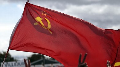 PHOTO: A man flashes the victory sign and waves a socialist flag at a political event organized by the French communist party September 18, 2011 in La Courneuve, outside Paris.