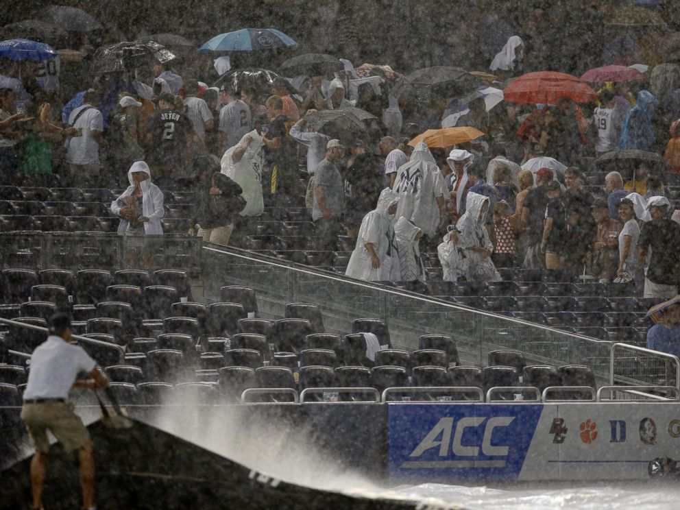 PHOTO: Fans scramble for cover as a rainstorm interrupts the fifth inning of a baseball game between the Texas Rangers and the New York Yankees at Yankee Stadium in New York, July 23, 2014.