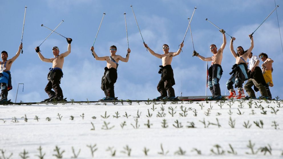 PHOTO:Course workers take off their shirts to enjoy the warm weather as they prepare the landing hill before the mens Nordic combined normal hill training jump at the RusSki Gorki Jump Center at the 2014 Sochi Winter Olympics.