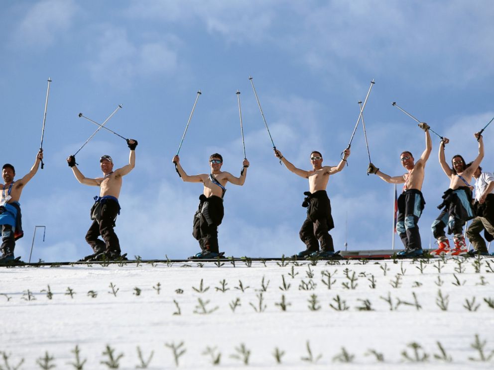 PHOTO:Course workers take off their shirts to enjoy the warm weather as they prepare the landing hill before the mens Nordic combined normal hill training jump at the RusSki Gorki Jump Center at the 2014 Sochi Winter Olympics.