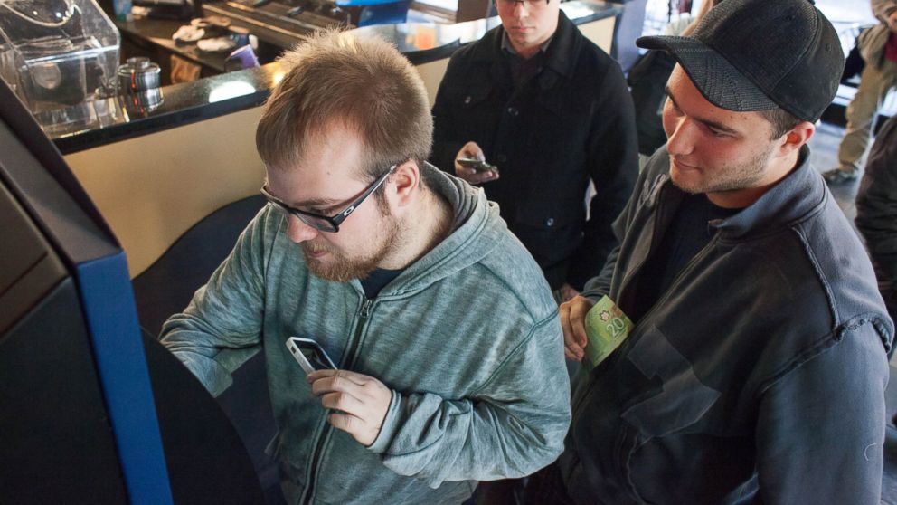 PHOTO: Curtis Machek, left, uses the worlds first bitcoin ATM at Waves Coffee House, Oct. 29, 2013, in Vancouver, British Columbia. 