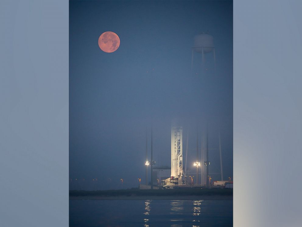 PHOTO: The full Moon sets in the fog behind the Orbital Sciences Corporation Antares rocket, with the Cygnus spacecraft onboard, Saturday, July 12, 2014, launch Pad-0A, NASAs Wallops Flight Facility in Virginia.