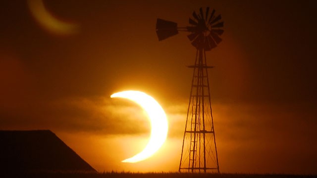 PHOTO: The sun sets behind a barn and windmill on Sunday, May 20, 2012, southwest of Ellis, Kans, during a partial solar eclipse.
