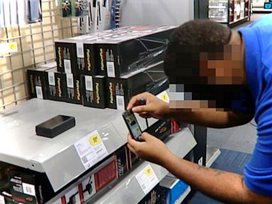 PHOTO: Best Buy employees snap photos of the Useless Plastic Box, which was put on shelves by a man who goes by Plastic Jesus.
