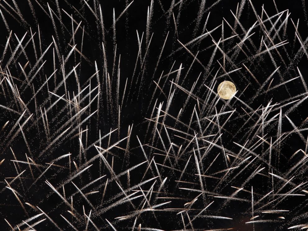 PHOTO: Fireworks streak past in front of the supermoon outside the town of Mosta in central Matla as the town celebrates the feast of its patron saint on August 10, 2014.