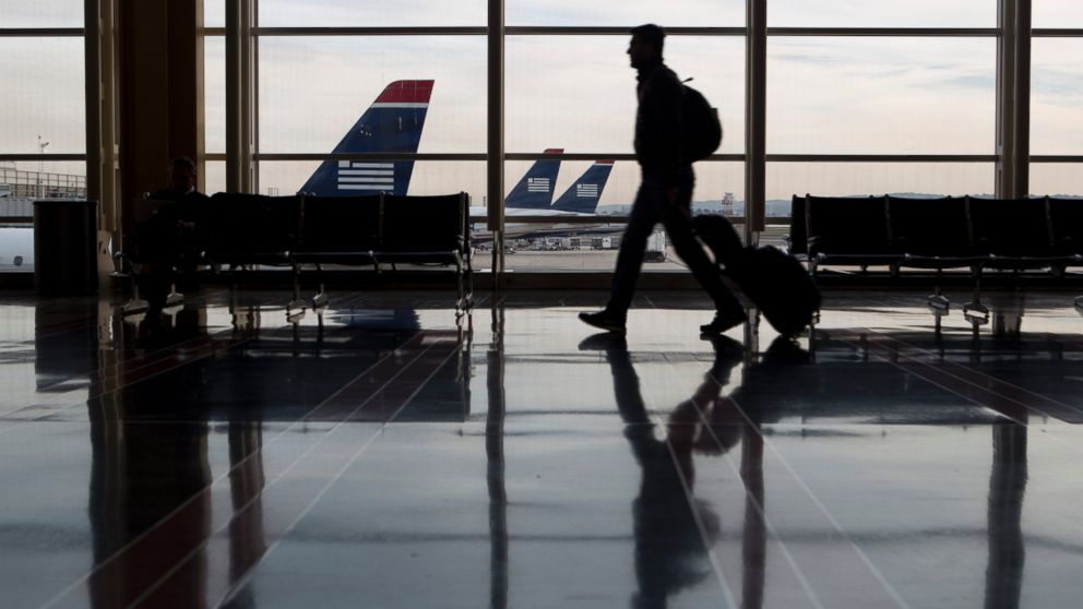 PHOTO: A traveler is seen walking past US Airways planes parked on the tarmac at Ronald Reagan National Airport in Washington, Nov. 15, 2013.