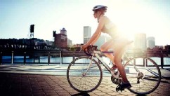 PHOTO: A woman commutes to work by bike, the evening sun setting over downtown Portland, Oregon and the Willamette River.