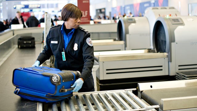 PHOTO: A Transportation Security Administration employee moves a checked piece of passenger luggage toward a scanning machine at a security check point at O'Hare International Airport in Chicago, Ill.