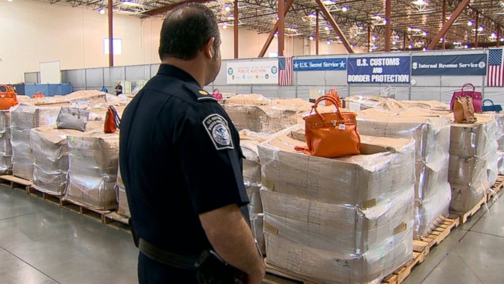 PHOTO: An officer looks at a shipment of seized counterfeit Hermes bags