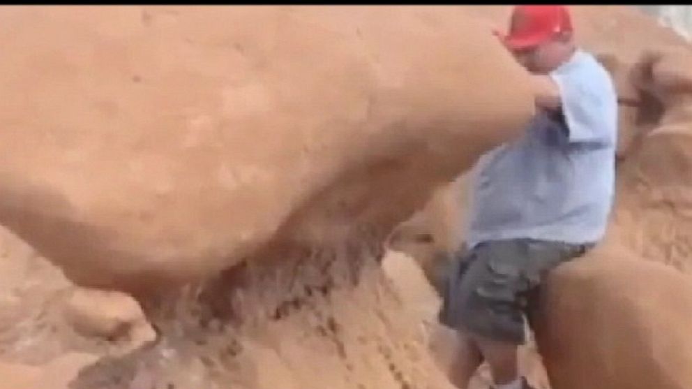 PHOTO: A Boy Scout troop leader, is shown pushing over a massive rock at Goblin Valley State Park