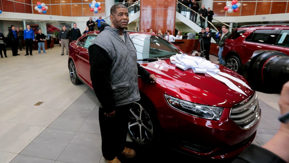 James Robertson, 56, stands next to his free 2015 Ford Taurus from Suburban Ford in Sterling Heights on Feb. 6, 2015, as part of a continuing showing of community support after a story of his dedication and journey on his 21 mile walk to and from work.