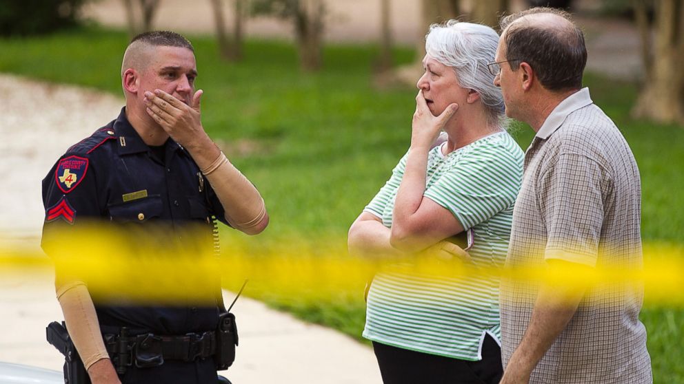 PHOTO: People stand with a law enforcement officer near the scene of a shooting, July 9, 2014, in Spring, Texas.