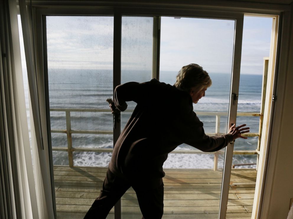 PHOTO: Eileen Horan shuts the door to her patio overlooking the Pacific Ocean after being forced to evacuate her apartment on Jan. 25, 2016, in Pacifica, Calif.