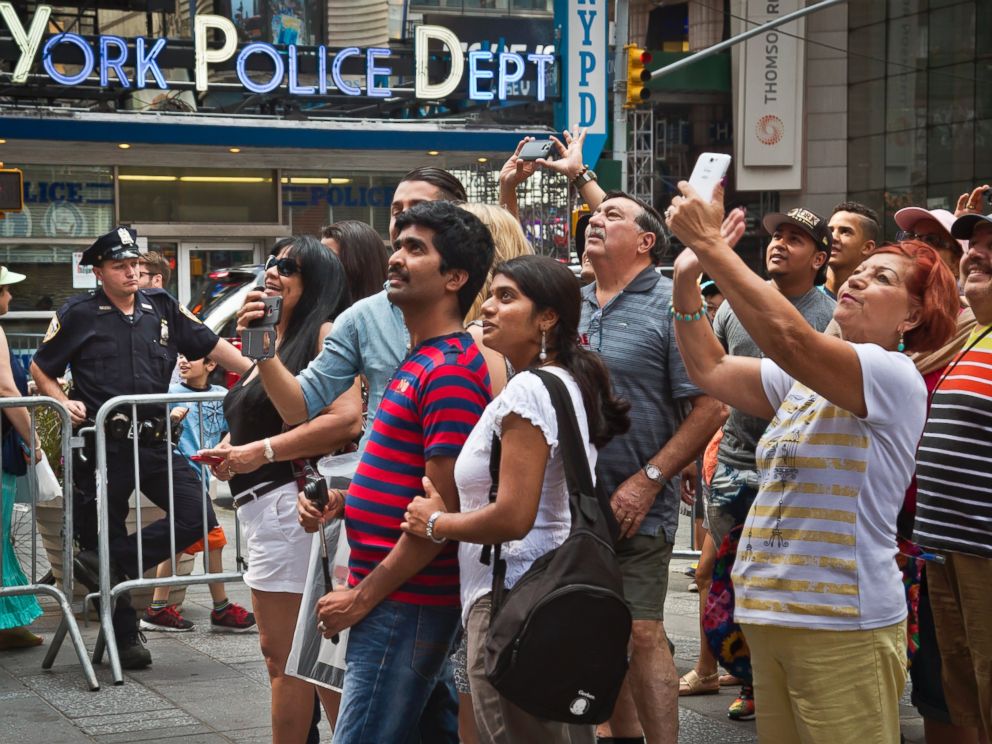 PHOTO: A New York police officer stands watch as visitors stage selfies for a giant monitor playback in Times Square, Friday, July 3, 2015, in New York.