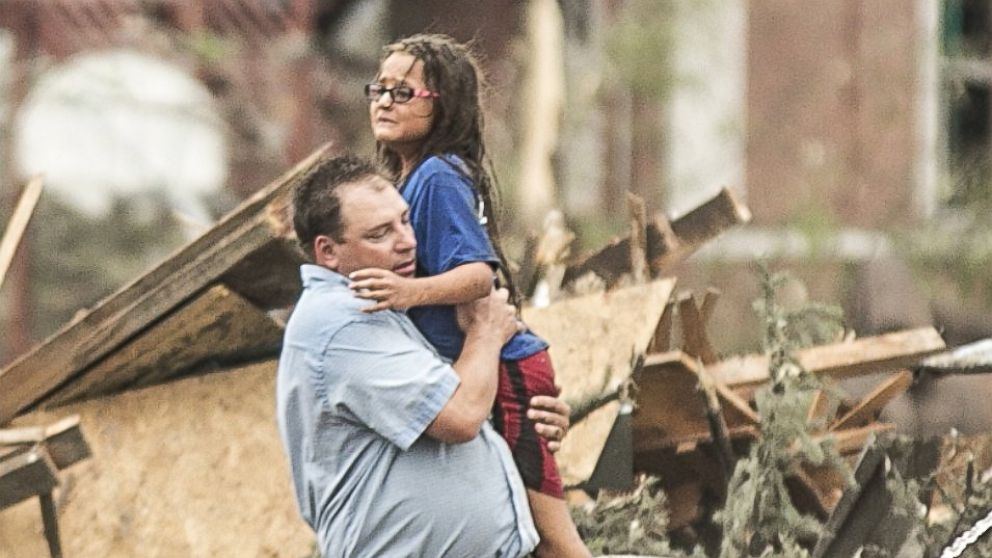 PHOTO: A man holds a girl after she was pulled from the basement of her destroyed home in Pilger, Neb.,June 16, 2014.