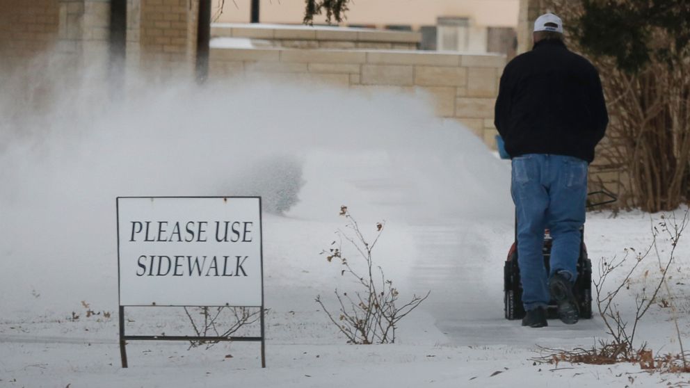 PHOTO: A worker clears snow from a sidewalk at the St. Lawrence Catholic Campus Center near the University of Kansas in Lawrence, Kan., March 2, 2014.