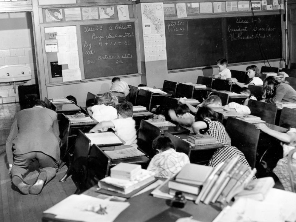 PHOTO: Sixth grade students crouch under or beside their desks along with their teacher as they act out a scene from the Federal Civil Defense administration film Duck and Cover in the Queens, Nov. 21, 1951.