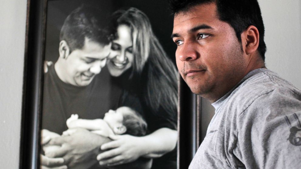 PHOTO: Erick Munoz stands with an undated photograph of himself, left, with wife Marlise and their son Mateo, in Haltom City, Texas.