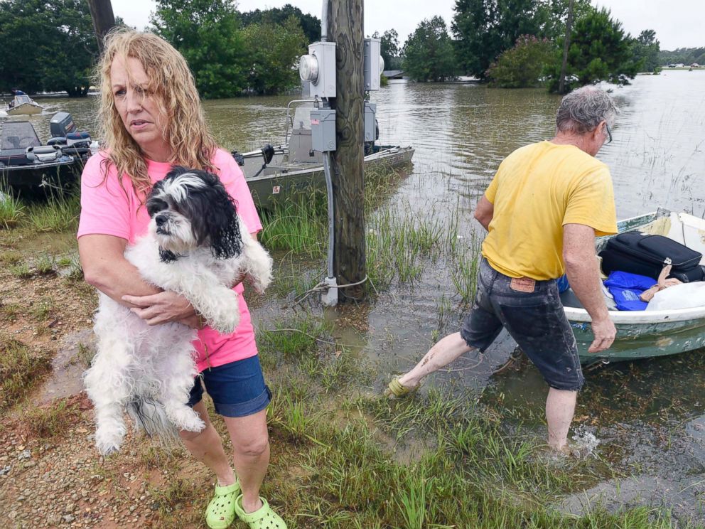 PHOTO: Tammie Wise holds her dog Mikey, after Jeffrey Lesage, right, boated them to safety in Central, Louisiana, Aug. 13, 2016. 
