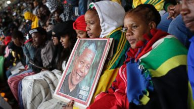 PHOTO: People huddle under blankets during the memorial service for former South African president Nelson Mandela at the FNB Stadium in Soweto, near Johannesburg, South Africa, Dec. 10, 2013.