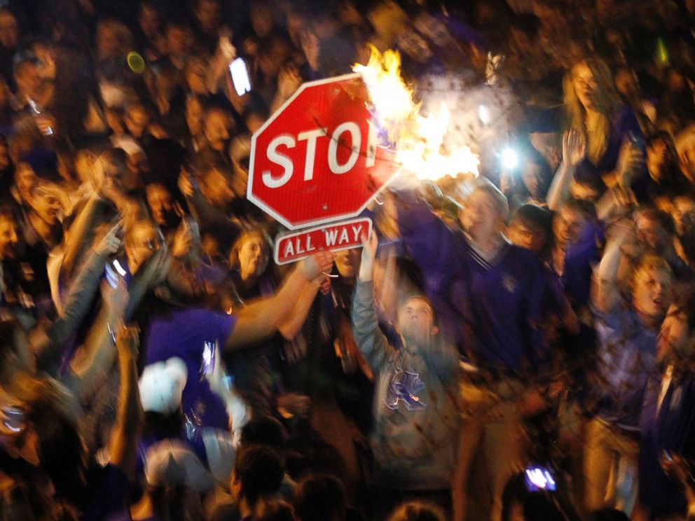 PHOTO: Kentucky fans wave a stop sign with a burning shirt near the University of Kentucky campus, Saturday, April 5, 2014, in Lexington, Ky.