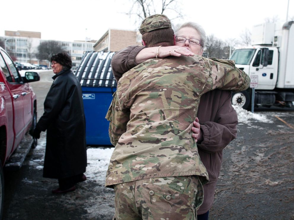 PHOTO: Michigan National Guard Staff Sergeant William Phillips gets a hug from a Flint resident after helping her carry bottled water to her car at a Flint Fire Station on Jan. 13, 2016 in Flint, Mich.