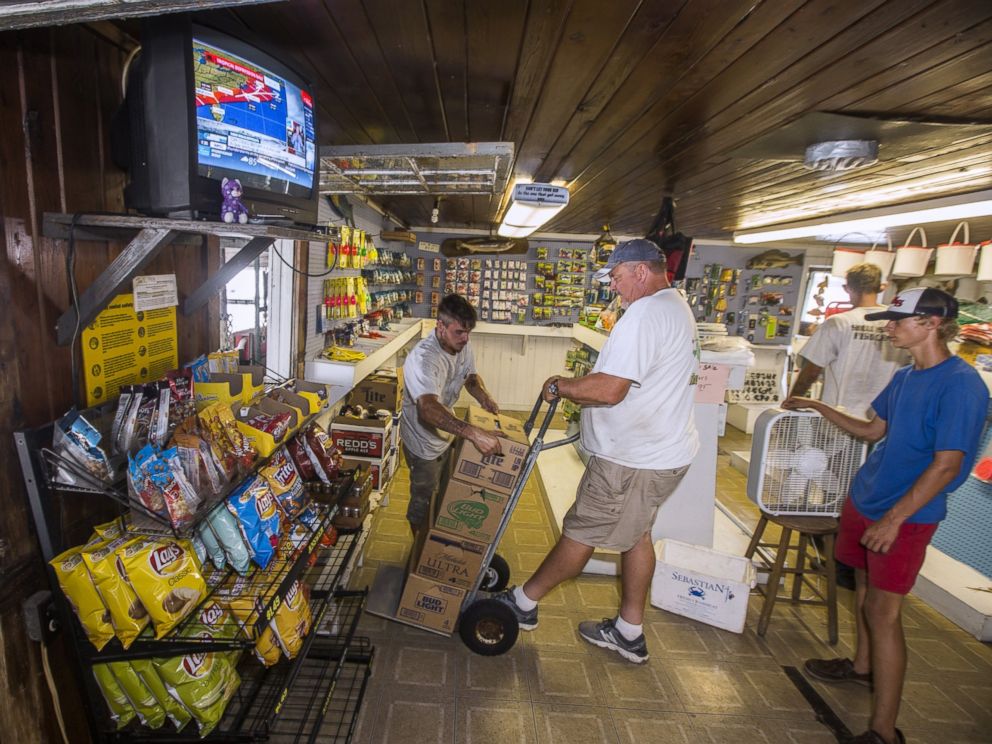 PHOTO: Des avertissements d'ouragan jouent à la télévision tandis que Tim Rozelle, à gauche, des piles de la bière sur un panier détenu par Murray Stokes, le 31 août 2016 à Saint Marks, Floride. 