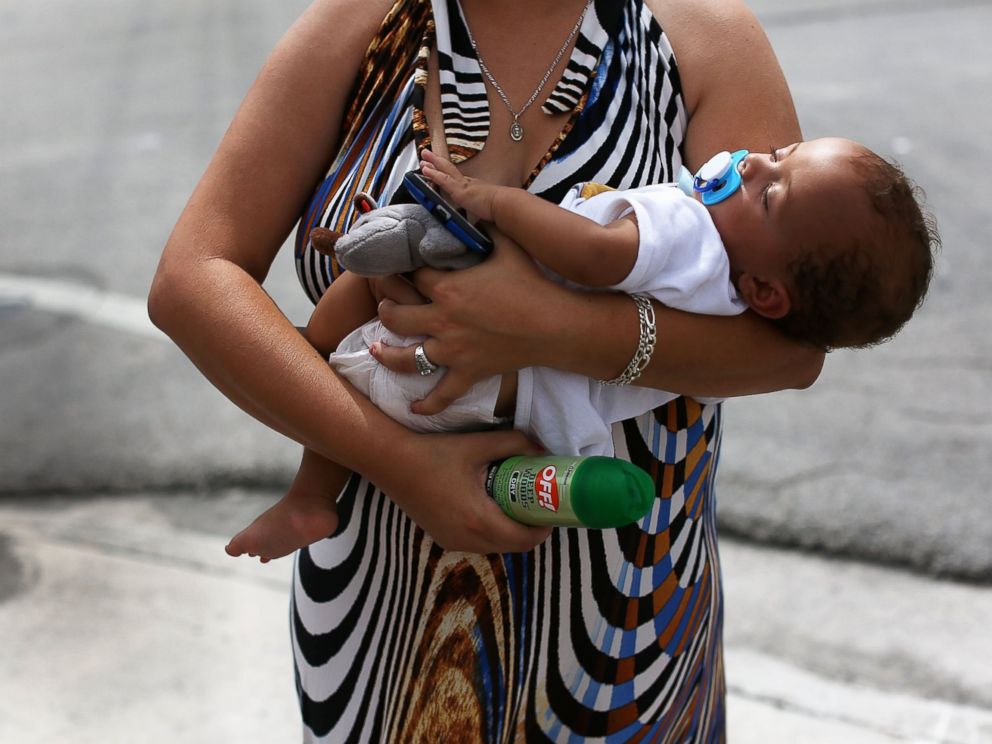 PHOTO: Barbara Betancourt holds her baby Daniel Valdes after being given a can of insect repellent by James Bernat, a City of Miami police officer