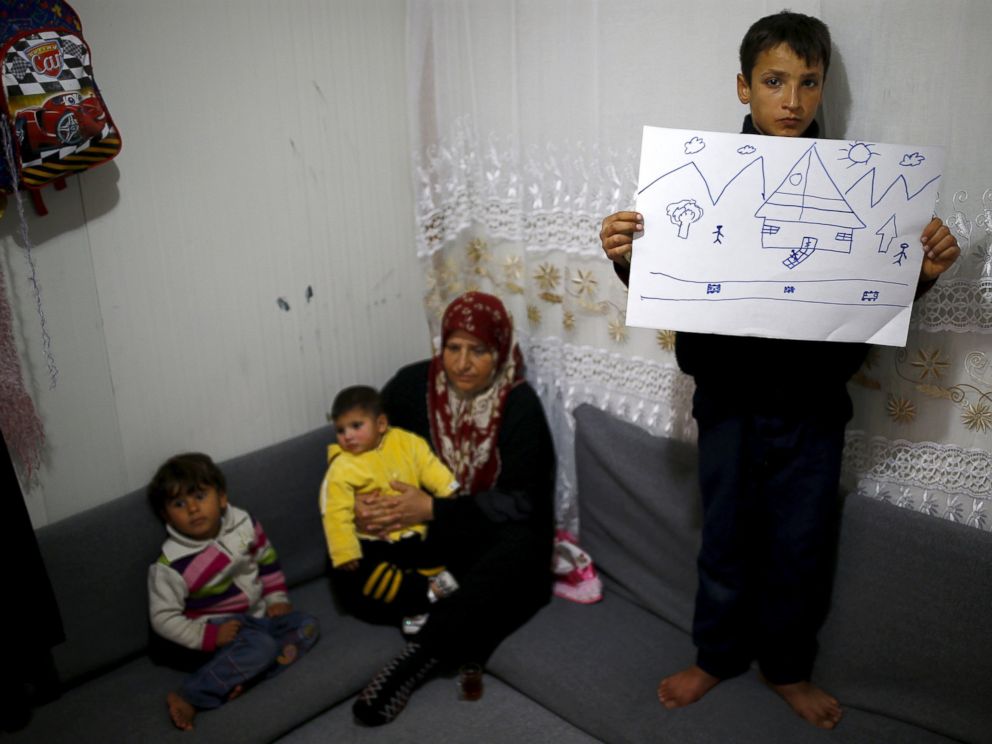 PHOTO: Syrian refugee Ahmet Cemal, 12, shows a drawing of home as his mother and his two brothers sit next to him in their tent in Nizip refugee camp in Gaziantep province, Turkey, Dec. 13, 2015.