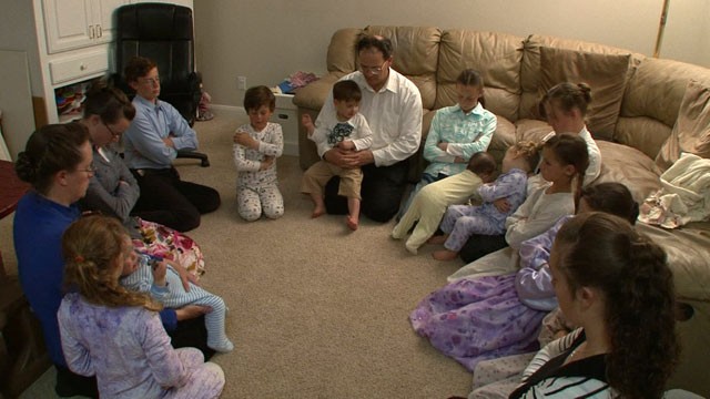 PHOTO: Michael Cawley avec certains de ses épouses et plusieurs de ses enfants prient lors d'un récent dimanche soir.