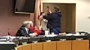 PHOTO Ginger Littletons attempt to hinder a gunmans attack on her co-workers by hitting him her purse is shown here in a video still.