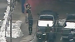 PHOTO In this grab from a dramatic video the suspect is shown holding gun to the head of hostage outside the bank. Hostage escapes after robber slips. Hes then shot.
