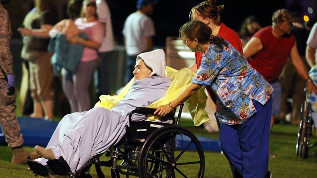  Emergency workers assist an elderly person at a staging area at a local school stadium Wednesday, April 17, 2013, in West, Texas.