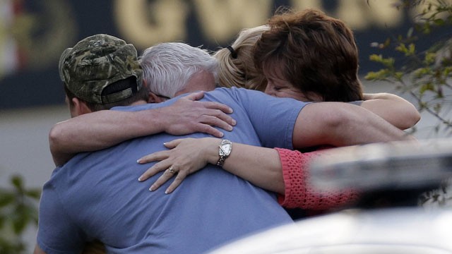 PHOTO: A group of people huddle together after an explosion and gunshots were heard near the scene where a man was holding four firefighters hostage Wednesday, April 10, 2013 in Suwanee, Ga.