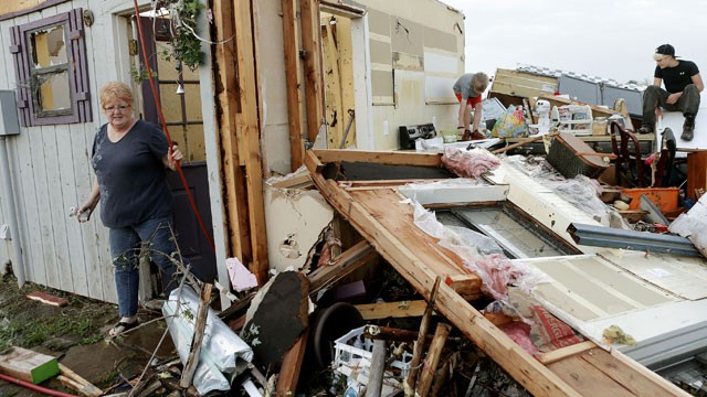 PHOTO: Marlena Hodson walks out of her home as her grandsons, Campbell Miller, 10, and Dillon Miller, 13, at right, help her sort through belongings after a tornado damaged her home Carney Okla., on Sunday, May 19, 2013.