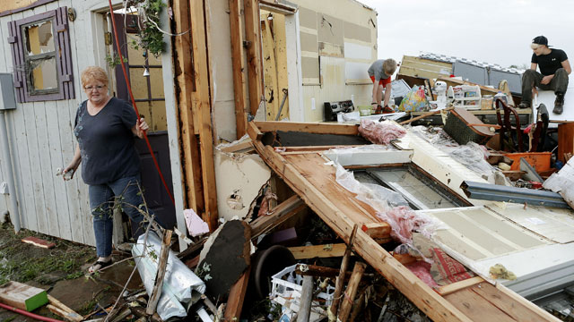 PHOTO: Marlena Hodson walks out of her home as her grandsons, Campbell Miller, 10, and Dillon Miller, 13, at right, help her sort through belongings after a tornado damaged her home Carney Okla., on Sunday, May 19, 2013.