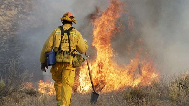 PHOTO: A Los Angeles County firefighter approaches a fire along a road in what has been called the Powerhouse fire in Lake Hughes, Calif., early Sunday, June 2, 2013.