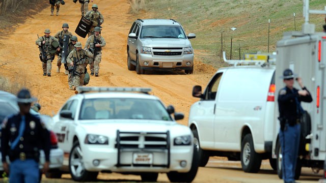 PHOTO: Heavily armed men move away from the suspects home at the scene of a Dale County hostage scene in Midland City, Ala., Jan. 30, 2013.