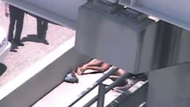 PHOTO: In this image taken from video, Miami police officers stand watch near Rudy Eugene, second from right, who was shot dead by a police officer when he refused to stop chewing on the face of Ronald Poppo, partially obscured by a railing, in Miami, May