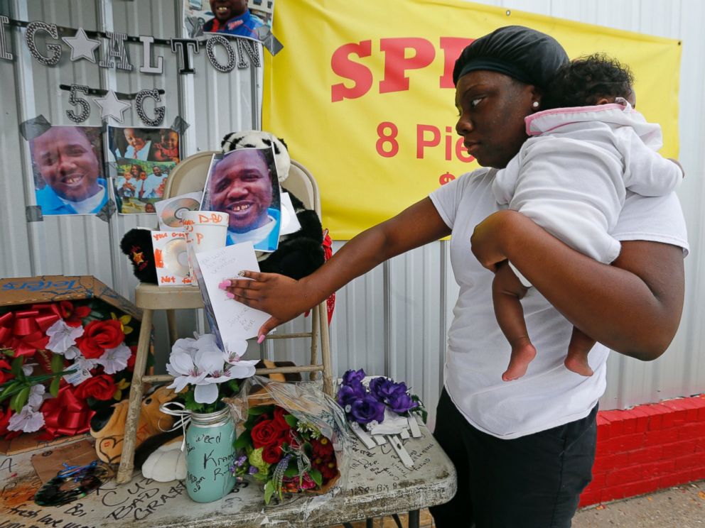 PHOTO: Shermire Reed, holding her daughter Zoe, places a card at a makeshift memorial outside a convenience store in Baton Rouge, Louisiana, July 6, 2016.