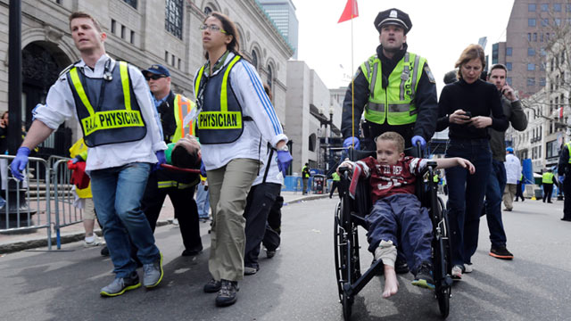 PHOTO: A Boston police officer wheels in injured boy down Boylston Street as medical workers carry an injured runner following an explosion during the 2013 Boston Marathon in Boston, April 15, 2013.