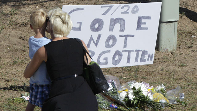 PHOTO: A woman and a child stand near a sign that reads "7/20 Gone Not Forgotten," near the movie theater where a gunman killed at least 12 people and wounded dozens of others in one of the deadliest mass shootings in recent U.S. history, Friday, July 20,