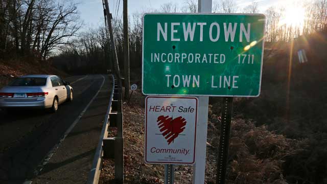 PHOTO: A car drives past the town line as the sun breaks the horizon, a day after a school shooting tragedy, in Newtown, Conn., Dec. 15, 2012.