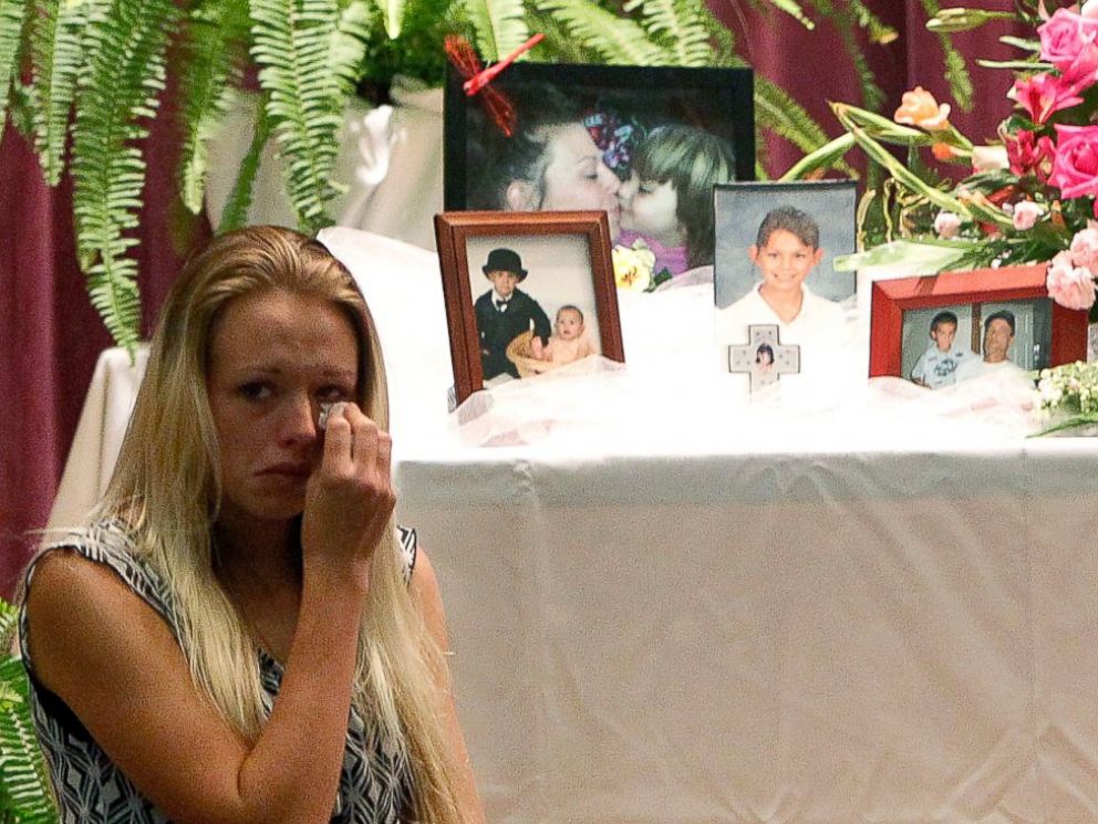 PHOTO: Mourners look at a display of photos during a memorial service at Bell High School for the victims of Thursdays shootings on Sunday, Sept. 21, 2014 in Bell, Fla.