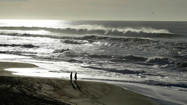 PHOTO: A couple walk along the North Beach as a helicopter searches for a man lost in the high surf, Jan. 1, 2013, at the Point Reyes National Seashore, Calif.